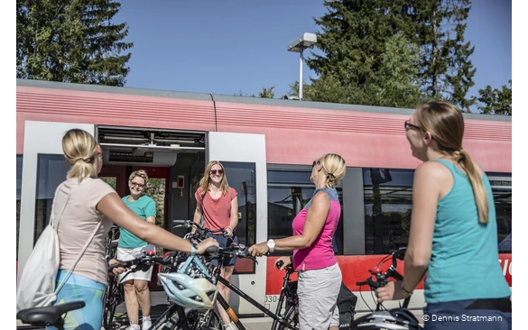 Eine Gruppe junger Frauen steigt mit ihren Fahrrädern aus dem Zug aus.