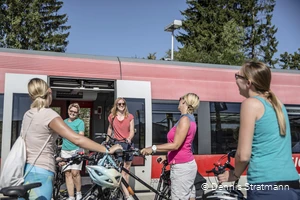 Eine Gruppe junger Frauen steigt mit ihren Fahrrädern aus dem Zug aus.